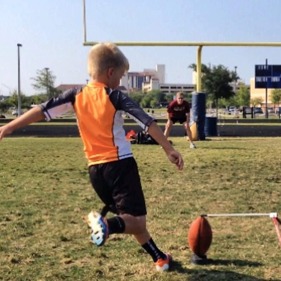 Young kicker kicking a football off a tee